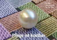 Eine glänzende Perle liegt auf einem gewobenen Hintergrund in Pastell-Farben. Am unteren Rand steht:" Pflege ist kostbar"